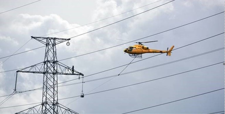 Helikopter trekt draden voor sterkere hoogspanning in de Polder