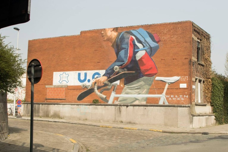 Straatkunst in Gentbrugge: enorme fietser met skateboard prijkt naast drukke brug