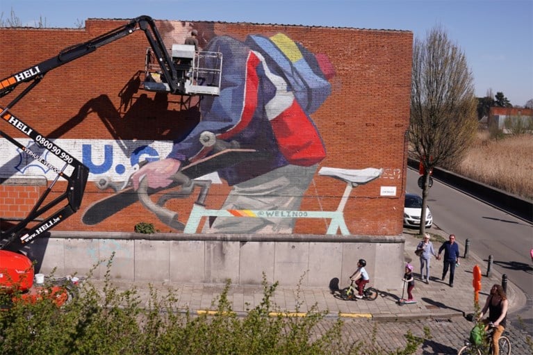 Straatkunst in Gentbrugge: enorme fietser met skateboard prijkt naast drukke brug