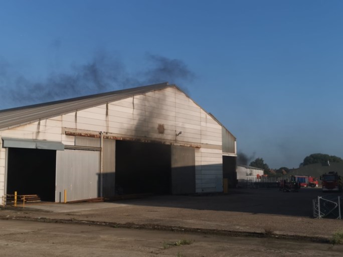 Brand in bouwbedrijf naast E17, zwarte rookpluim van ver zichtbaar