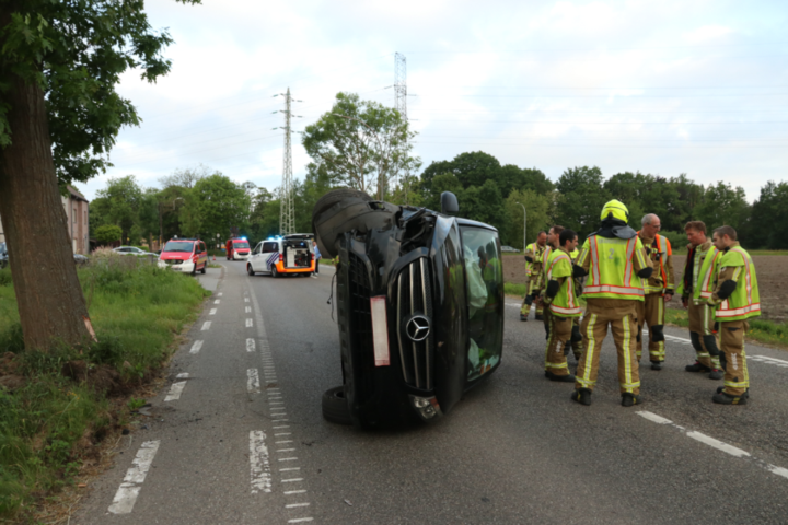 Bestelwagen op de flank na crash tegen boom